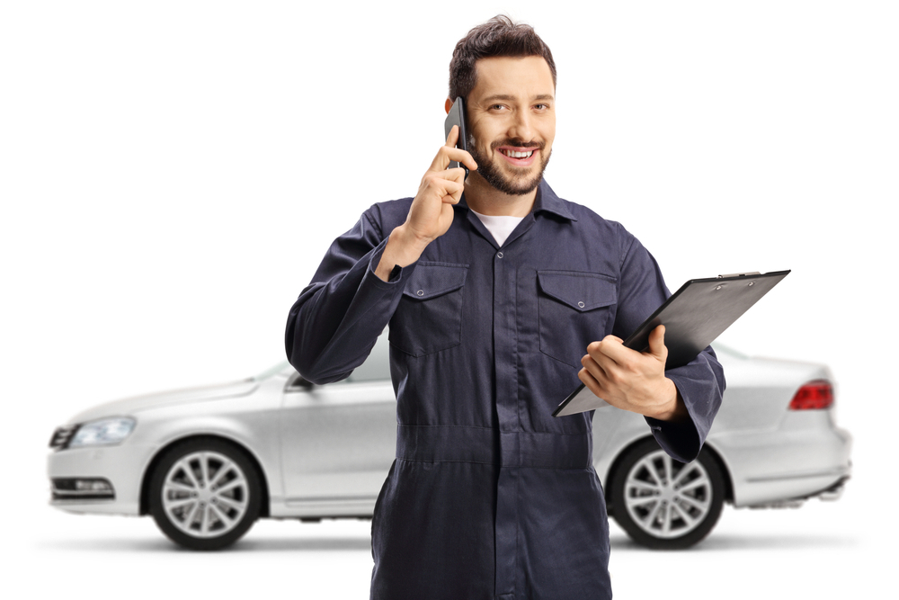 A man in auto glass repair service holding a phone - The Importance of Using High-Quality Materials in Auto Glass Repairs
