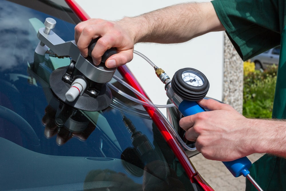 Professional worker repairing windshield on a car after stone-chipping damage