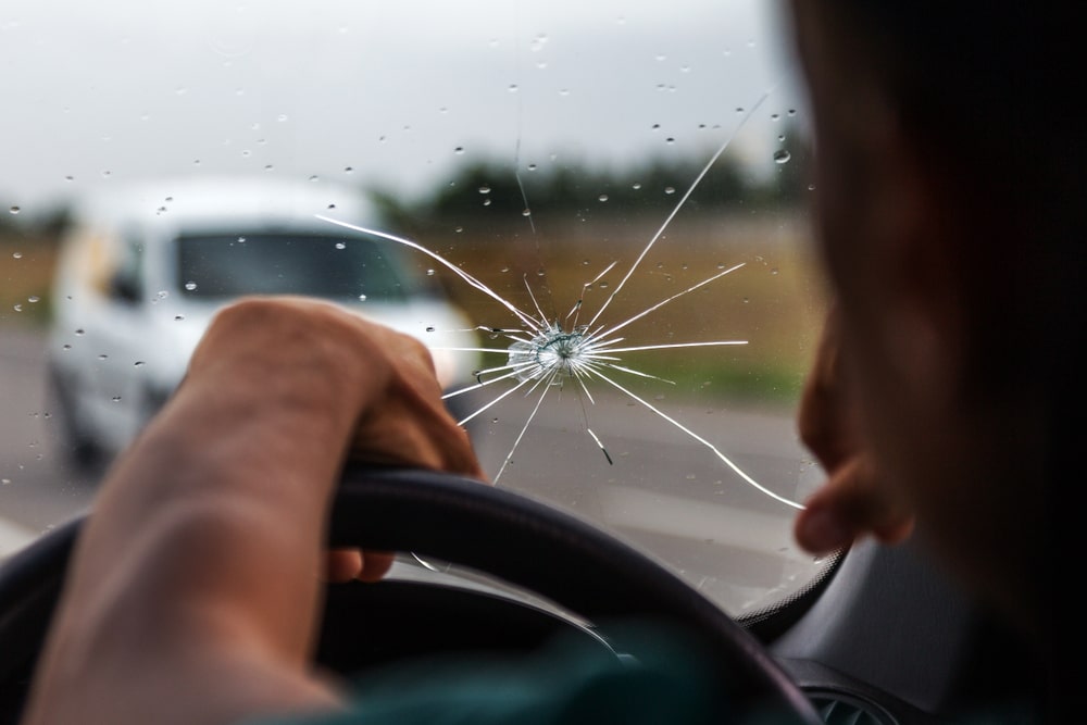 A car's damaged windshield with radial cracks and traces of impact, highlighting the need for Apex Auto Glass's quality repair services in New Orleans