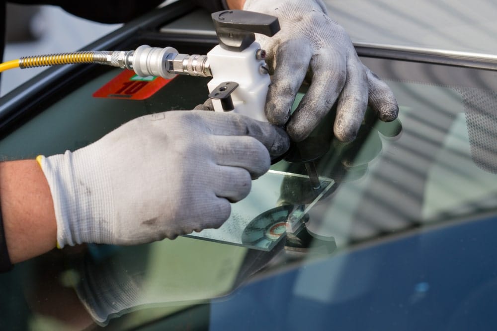A service agent doing a windshield repair with his material, repairing a dangerous crack in the windshield on location without a replacement